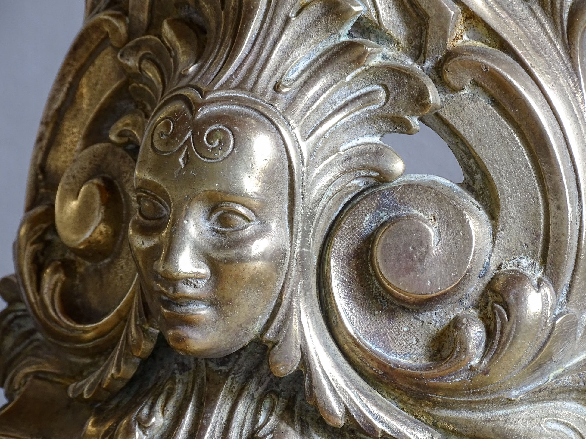 Pair of French antique brass lamps with ornate scrollwork and mask detail