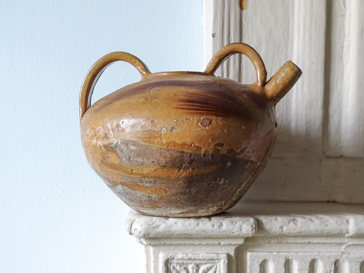 French antique earthenware pitcher or dourne with ochre yellow glaze, pictured on a country house fireplace.