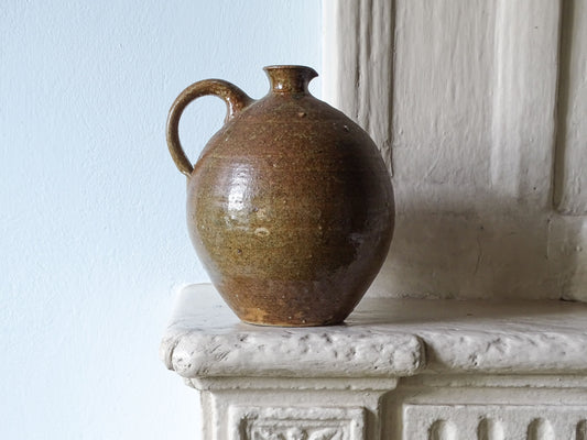 French antique ceramic pitcher with brown glaze and textured body, displayed on a country house fireplace