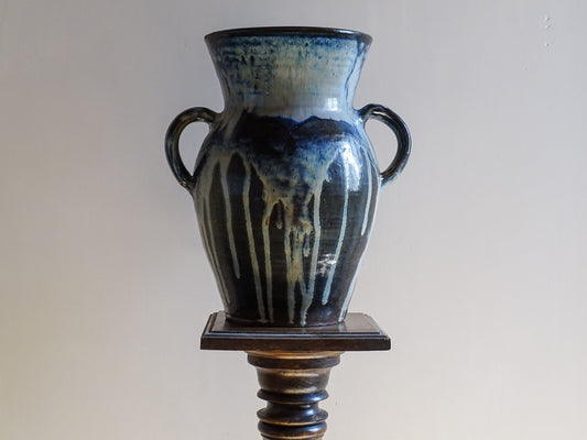 A large vintage studio pottery vase with a blue drip glaze. This stunning ceramic vase has a sculptural amphora form and twin handles, finished in a layered blue drip glaze.