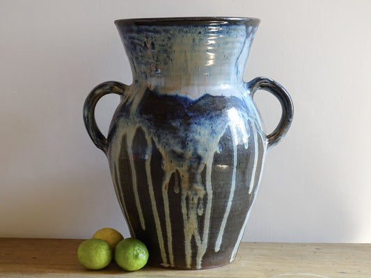 A large vintage studio pottery vase with a blue drip glaze. This stunning ceramic vase has a sculptural amphora form and twin handles, finished in a layered blue drip glaze.
