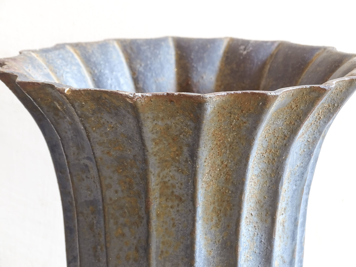 A sculptural pair of French antique cast iron urn planters, with fluted bowls set on stepped bases and raised on paw feet. These antique planters date to to the latter part of the 19th century. They have developed a deep, dark patina.