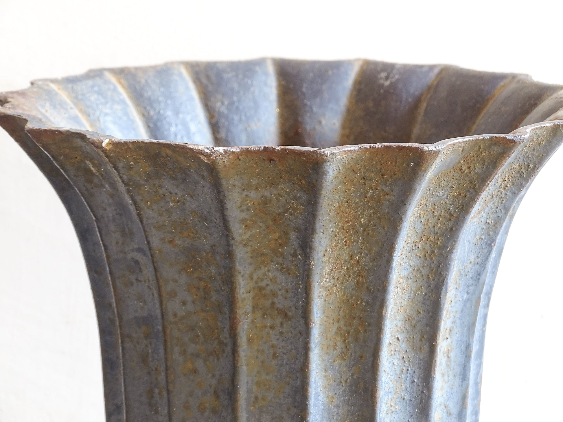 A sculptural pair of French antique cast iron urn planters, with fluted bowls set on stepped bases and raised on paw feet. These antique planters date to to the latter part of the 19th century. They have developed a deep, dark patina.