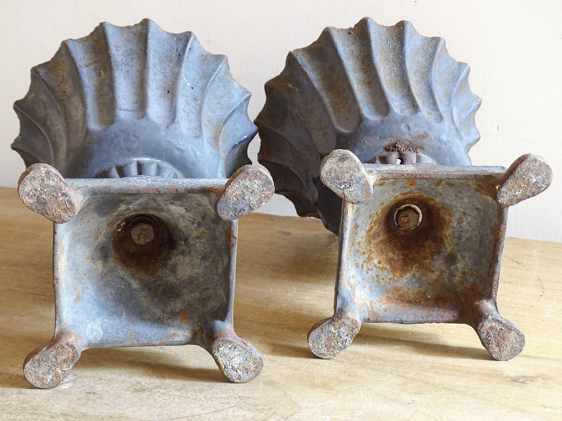 A sculptural pair of French antique cast iron urn planters, with fluted bowls set on stepped bases and raised on paw feet. These antique planters date to to the latter part of the 19th century. They have developed a deep, dark patina.