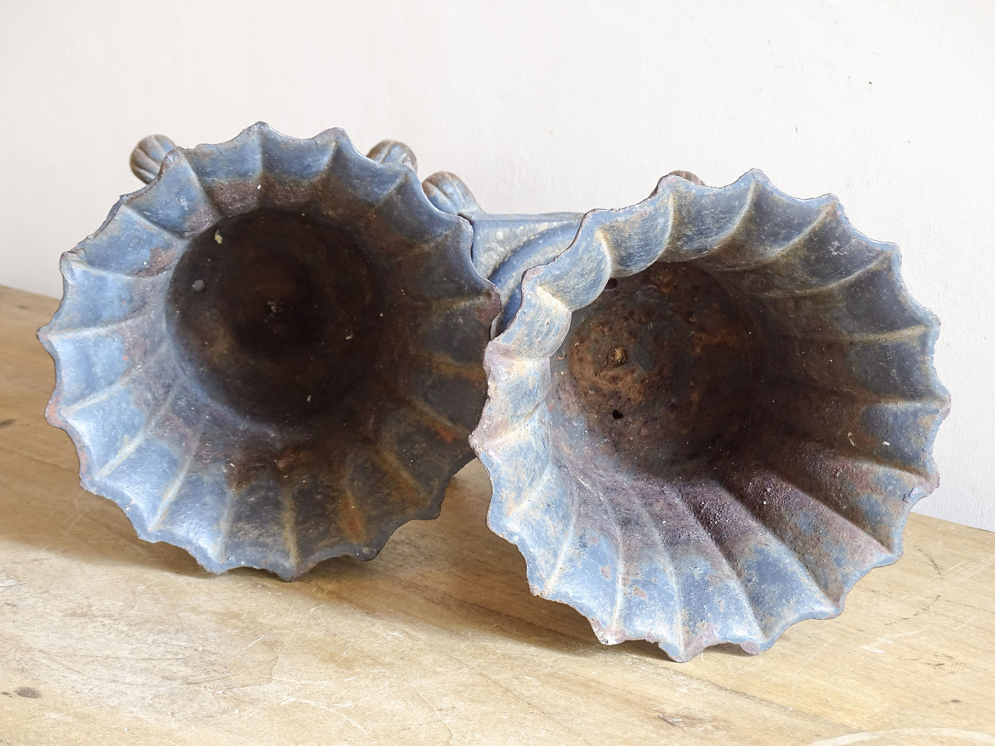 A sculptural pair of French antique cast iron urn planters, with fluted bowls set on stepped bases and raised on paw feet. These antique planters date to to the latter part of the 19th century. They have developed a deep, dark patina.