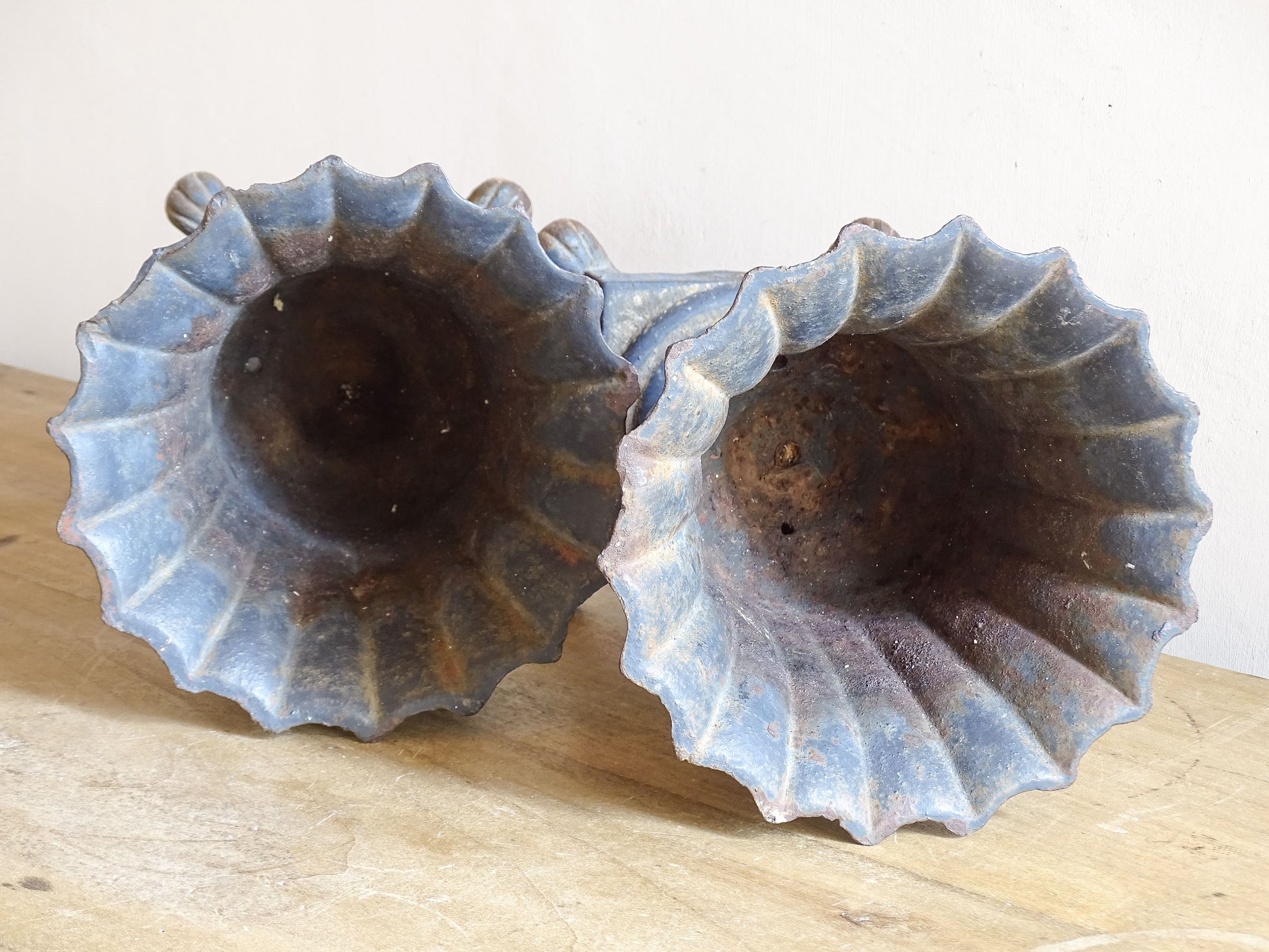 A sculptural pair of French antique cast iron urn planters, with fluted bowls set on stepped bases and raised on paw feet. These antique planters date to to the latter part of the 19th century. They have developed a deep, dark patina.