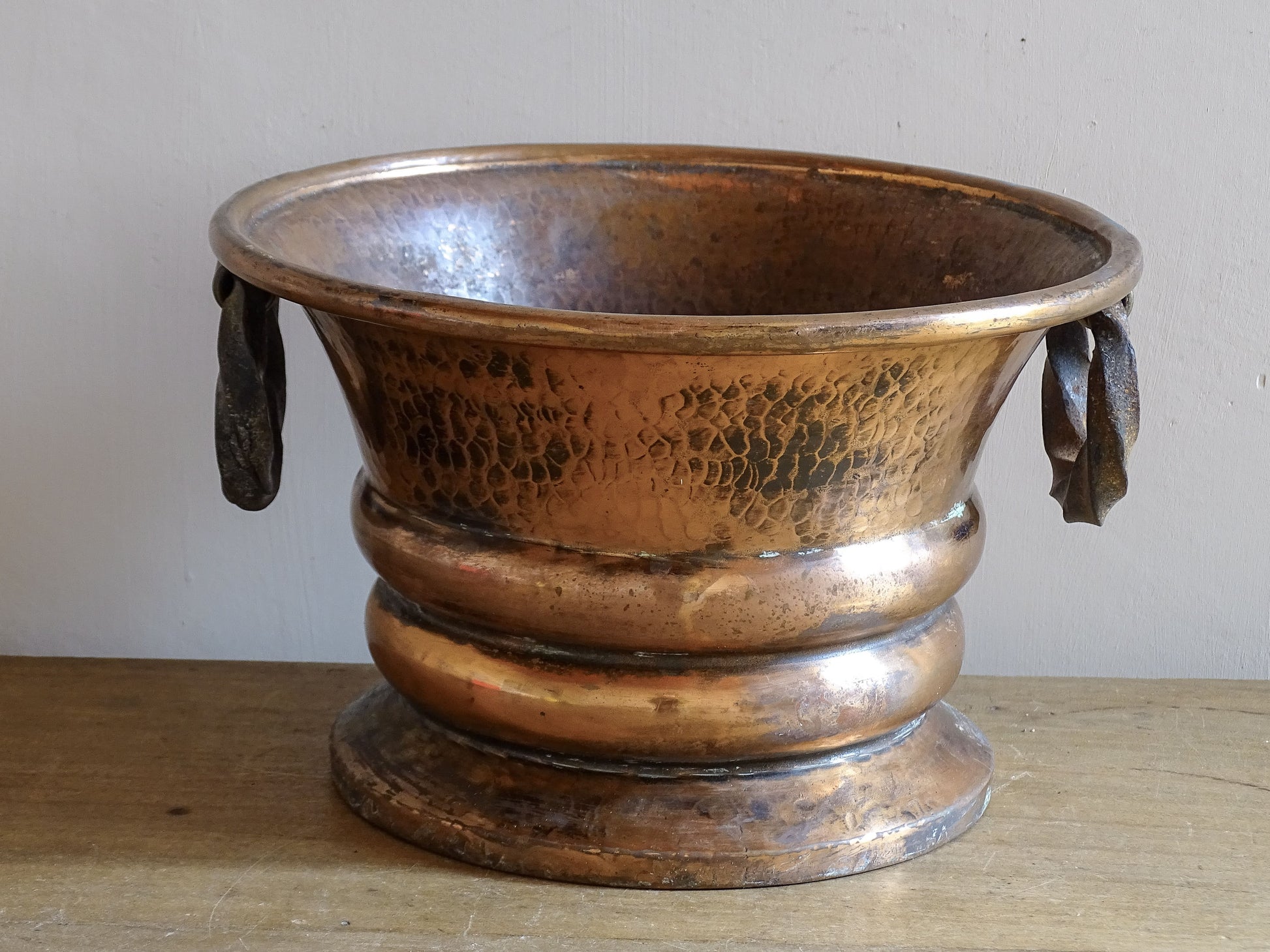 French antique hammered copper planter with iron handles. The copper has developed a rich, lived-in patina, with darker areas around the handles and base.