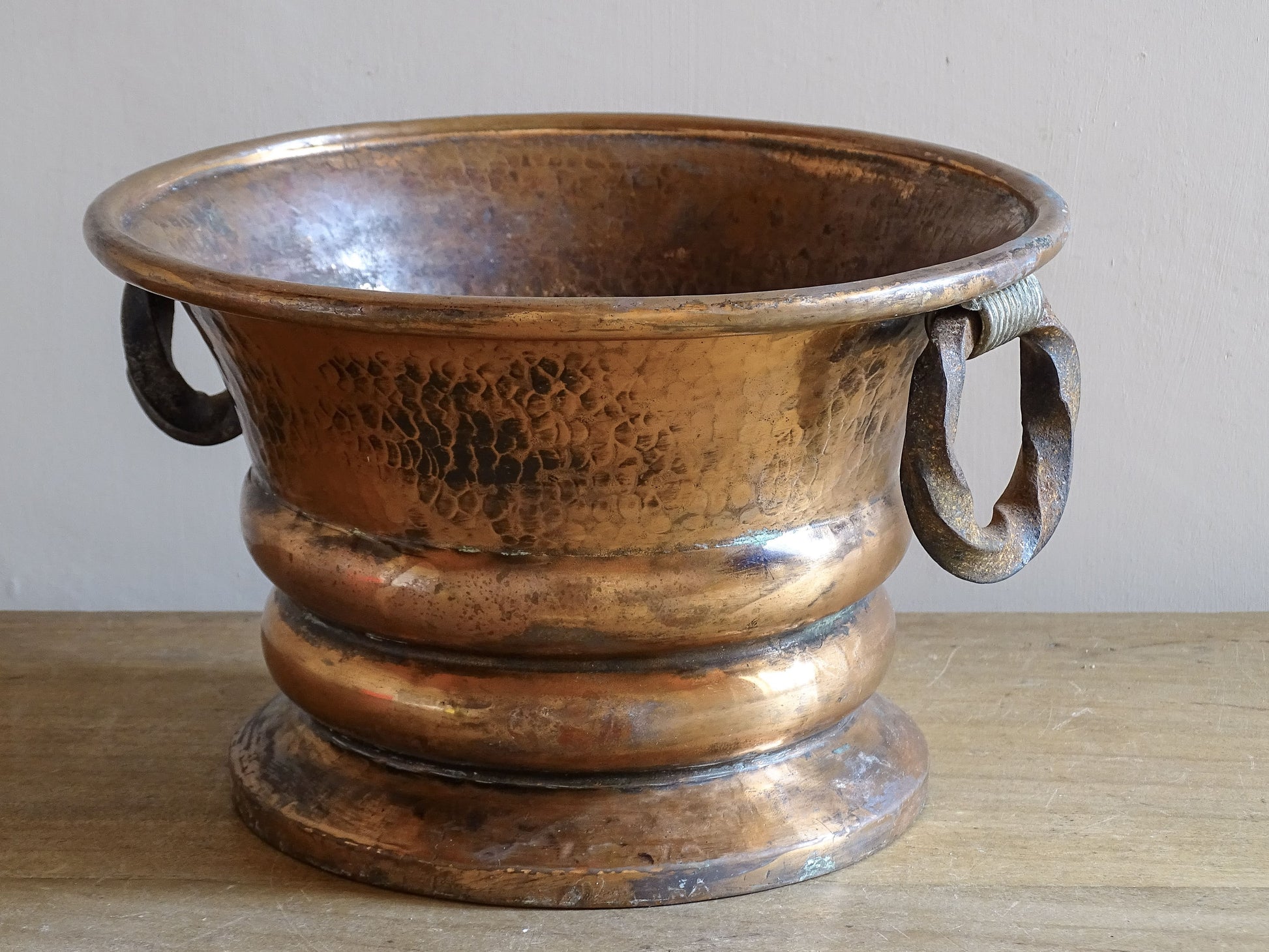 French antique hammered copper planter with iron handles. The copper has developed a rich, lived-in patina, with darker areas around the handles and base.