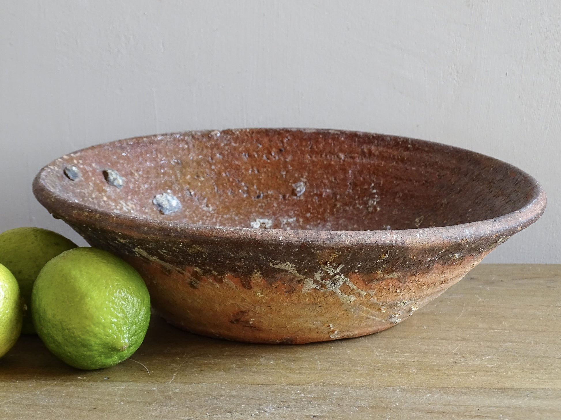 Early French pottery bowl styled with citrus on wooden surface