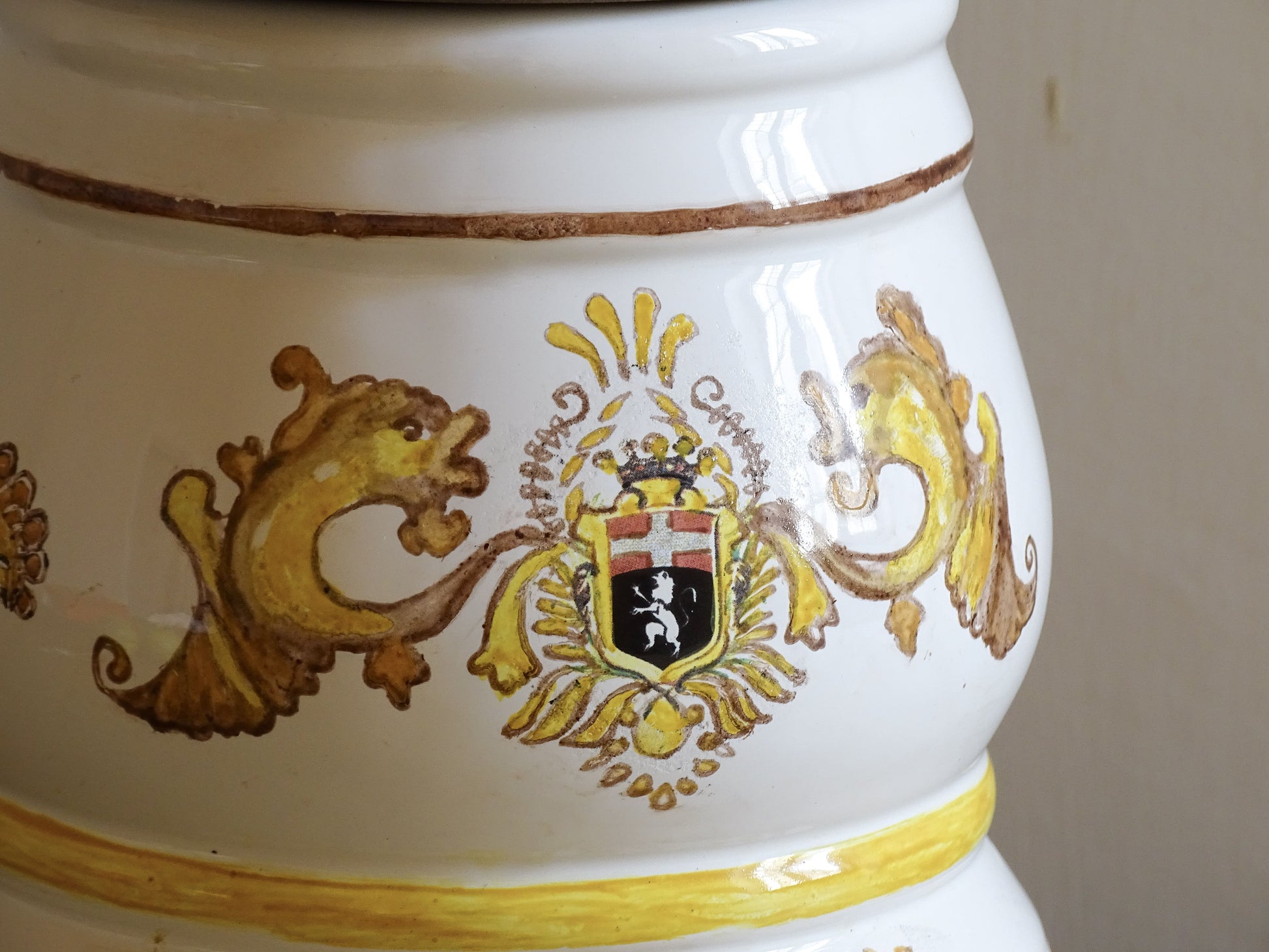 A vintage ceramic apothecary jar with hand-painted decoration and gilt lettering, with a wooden lid and base. Inspired by traditional European pharmacy vessels.