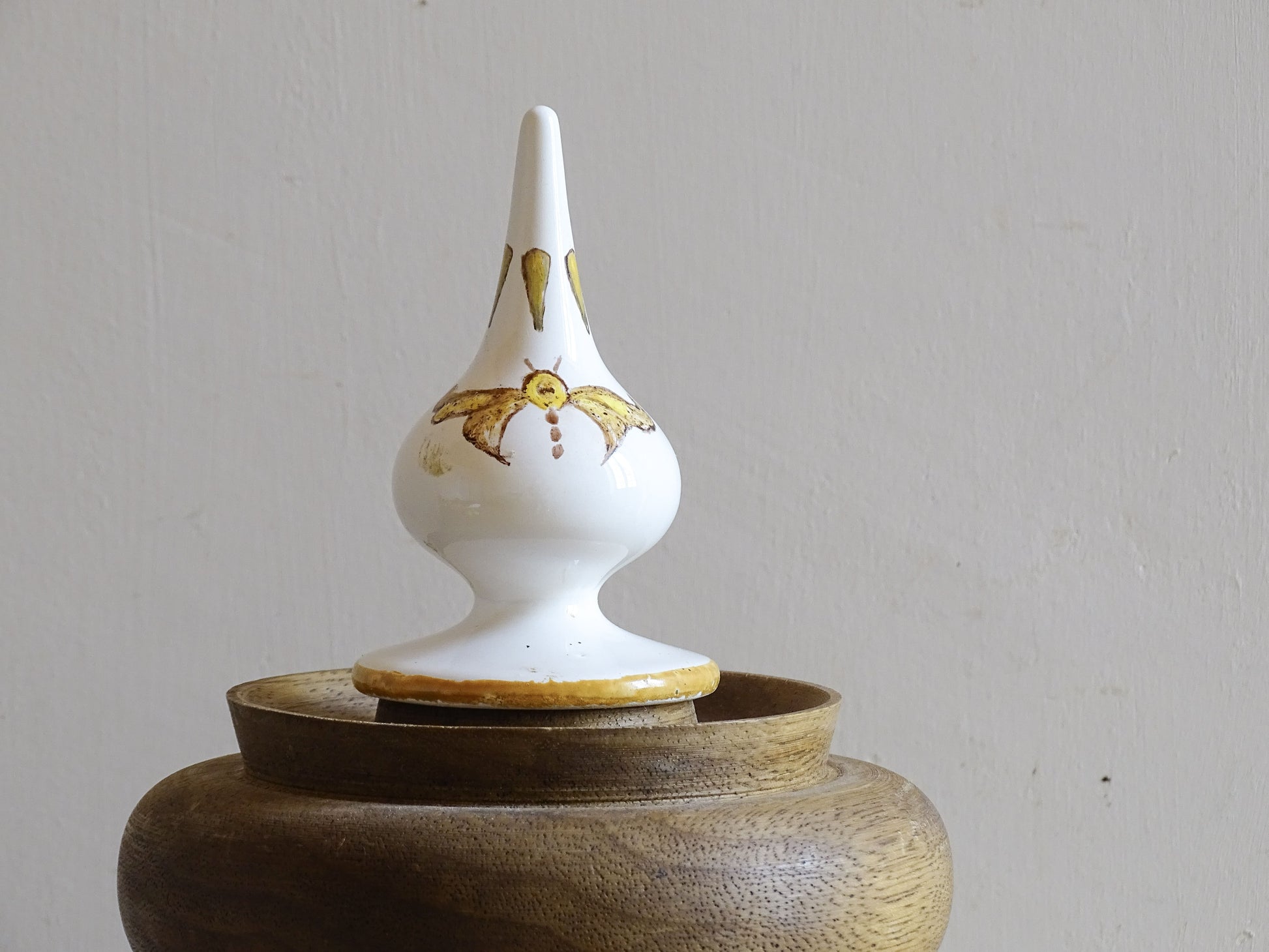 A vintage ceramic apothecary jar with hand-painted decoration and gilt lettering, with a wooden lid and base. Inspired by traditional European pharmacy vessels.