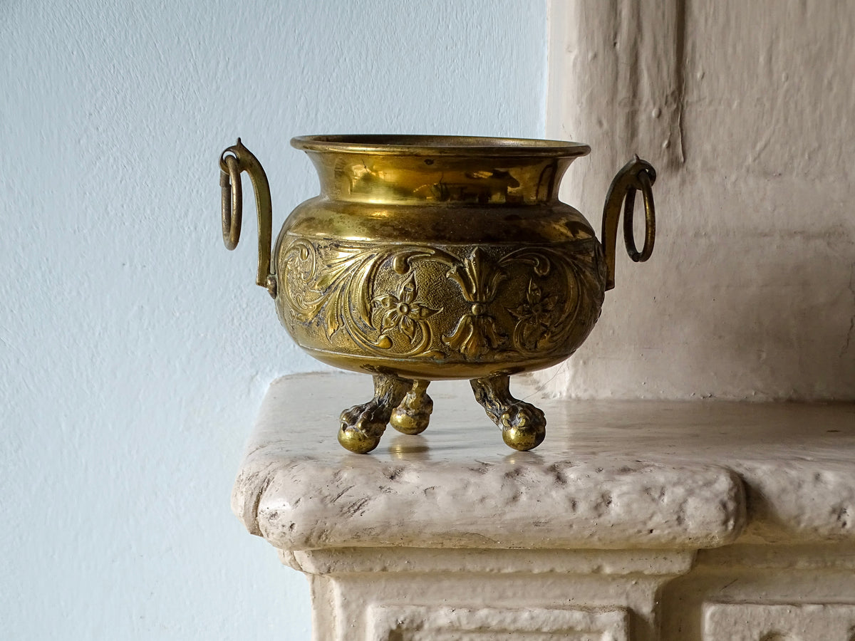 French antique brass planter with three claw and ball feet, pictured on a country house fireplace