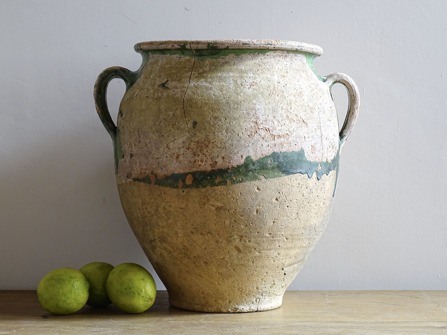 A French antique confit pot from the South West of France, dating to the early to mid 19th century. Hand-thrown in terracotta, the pot has a classic, gently tapered form with two loop handles and a slightly flared rim. 