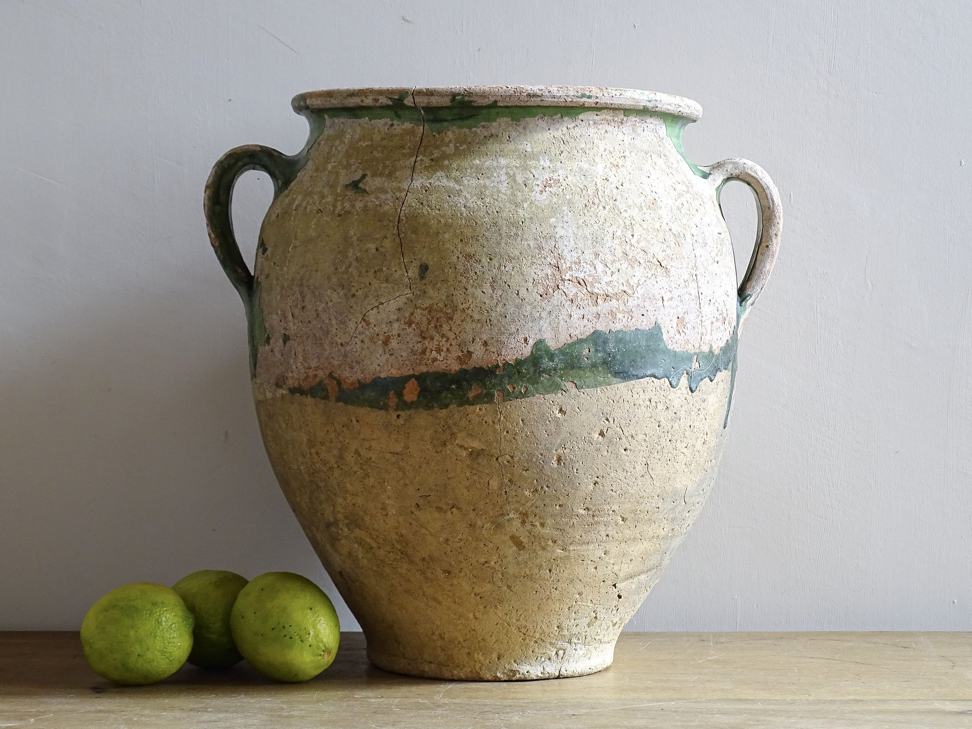 A French antique confit pot from the South West of France, dating to the early to mid 19th century. Hand-thrown in terracotta, the pot has a classic, gently tapered form with two loop handles and a slightly flared rim. 