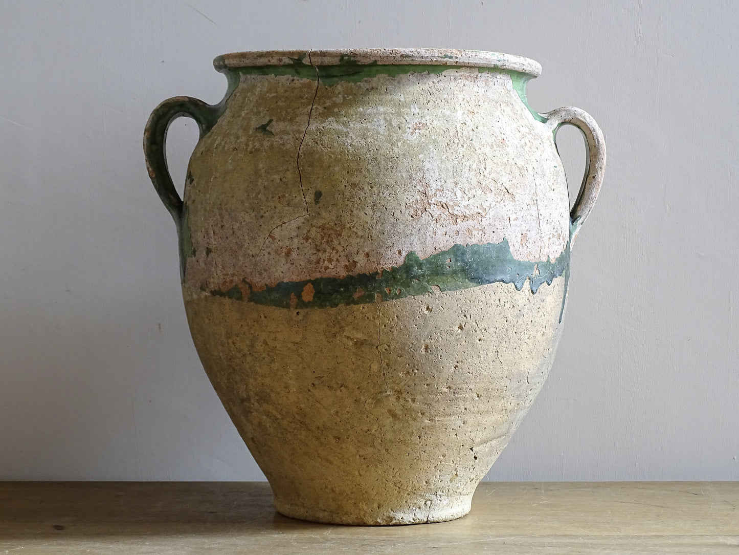 A French antique confit pot from the South West of France, dating to the early to mid 19th century. Hand-thrown in terracotta, the pot has a classic, gently tapered form with two loop handles and a slightly flared rim. 