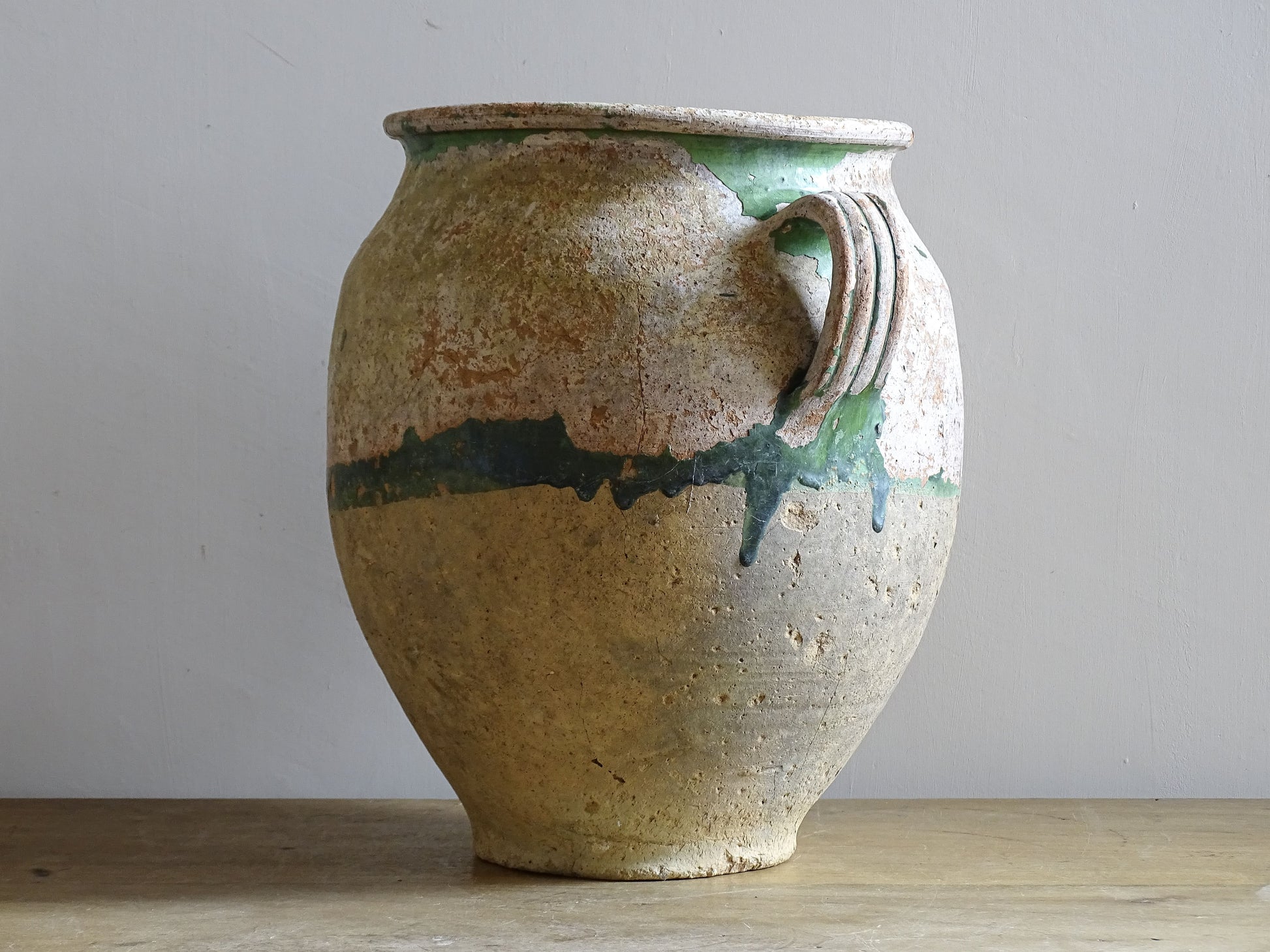 A French antique confit pot from the South West of France, dating to the early to mid 19th century. Hand-thrown in terracotta, the pot has a classic, gently tapered form with two loop handles and a slightly flared rim. 