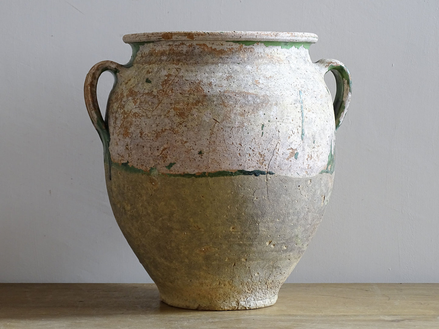A French antique confit pot from the South West of France, dating to the early to mid 19th century. Hand-thrown in terracotta, the pot has a classic, gently tapered form with two loop handles and a slightly flared rim. 