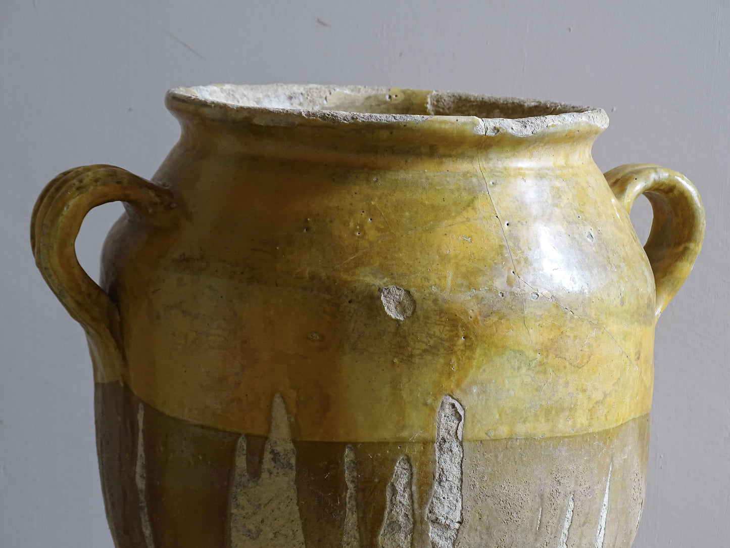 A large French antique confit pot in terracotta with two handles. Dating to the late 19th century and finished with a warm yellow glaze across the upper half.
