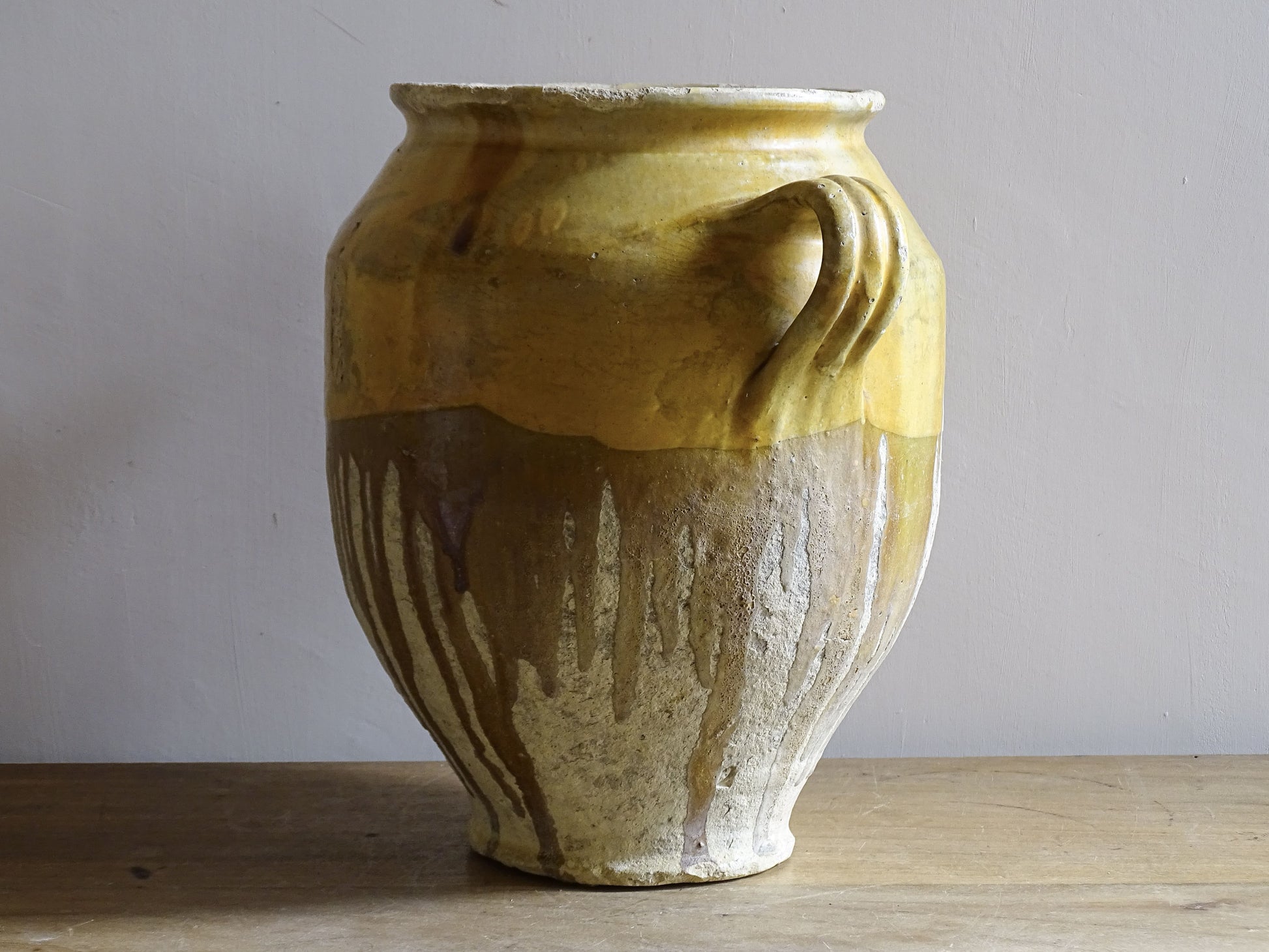 A large French antique confit pot in terracotta with two handles. Dating to the late 19th century and finished with a warm yellow glaze across the upper half.