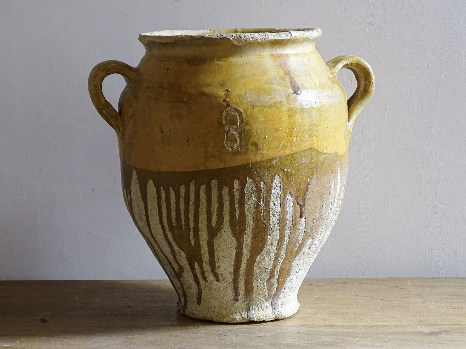 A large French antique confit pot in terracotta with two handles. Dating to the late 19th century and finished with a warm yellow glaze across the upper half.