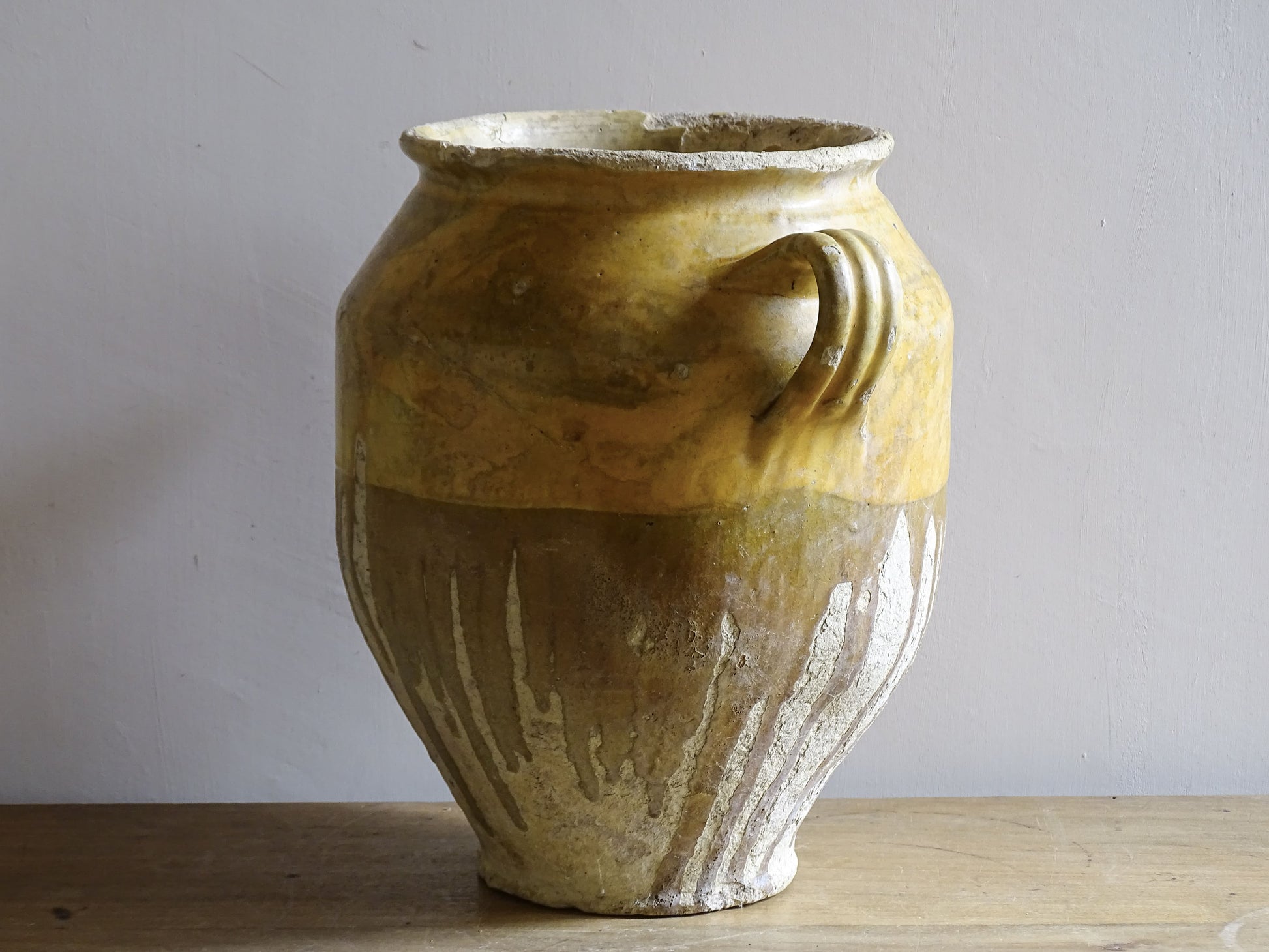 A large French antique confit pot in terracotta with two handles. Dating to the late 19th century and finished with a warm yellow glaze across the upper half.