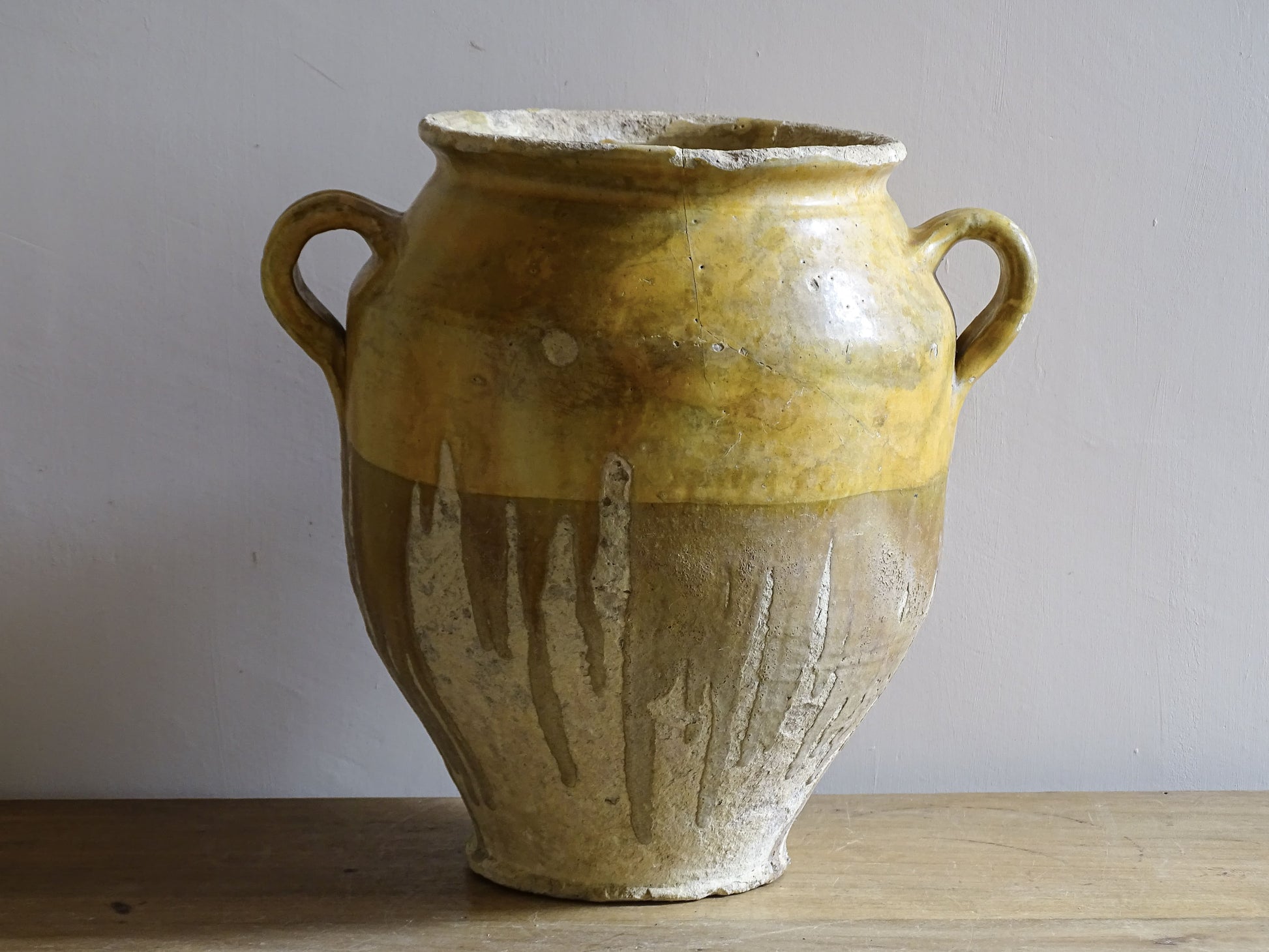 A large French antique confit pot in terracotta with two handles. Dating to the late 19th century and finished with a warm yellow glaze across the upper half.