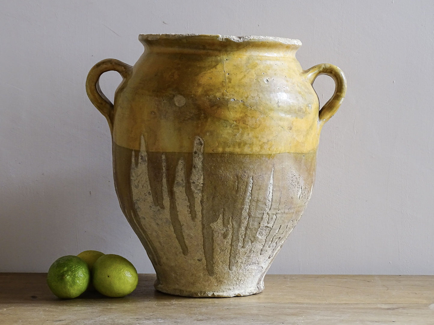 A large French antique confit pot in terracotta with two handles. Dating to the late 19th century and finished with a warm yellow glaze across the upper half.