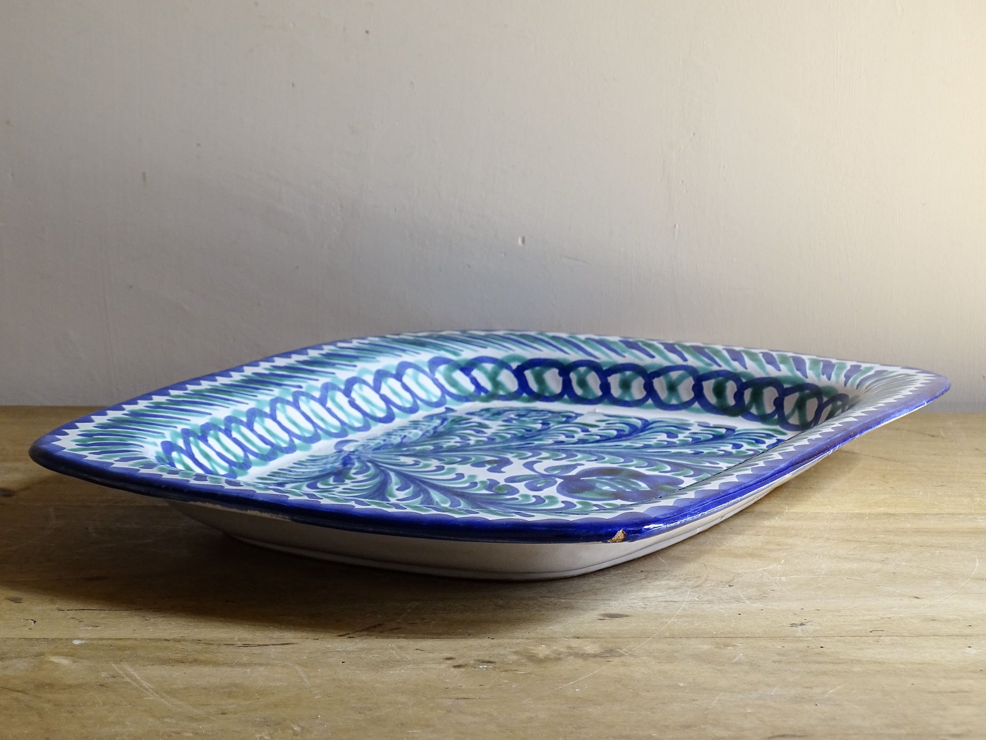 A striking Spanish vintage Fajalauza platter, hand-painted in cobalt blue and soft green on a white ground. The design features flowing foliate motifs and stylised floral details.