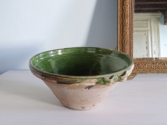 French antique ceramic tian bowl with green glaze interior, pictured next to a gold mirror 