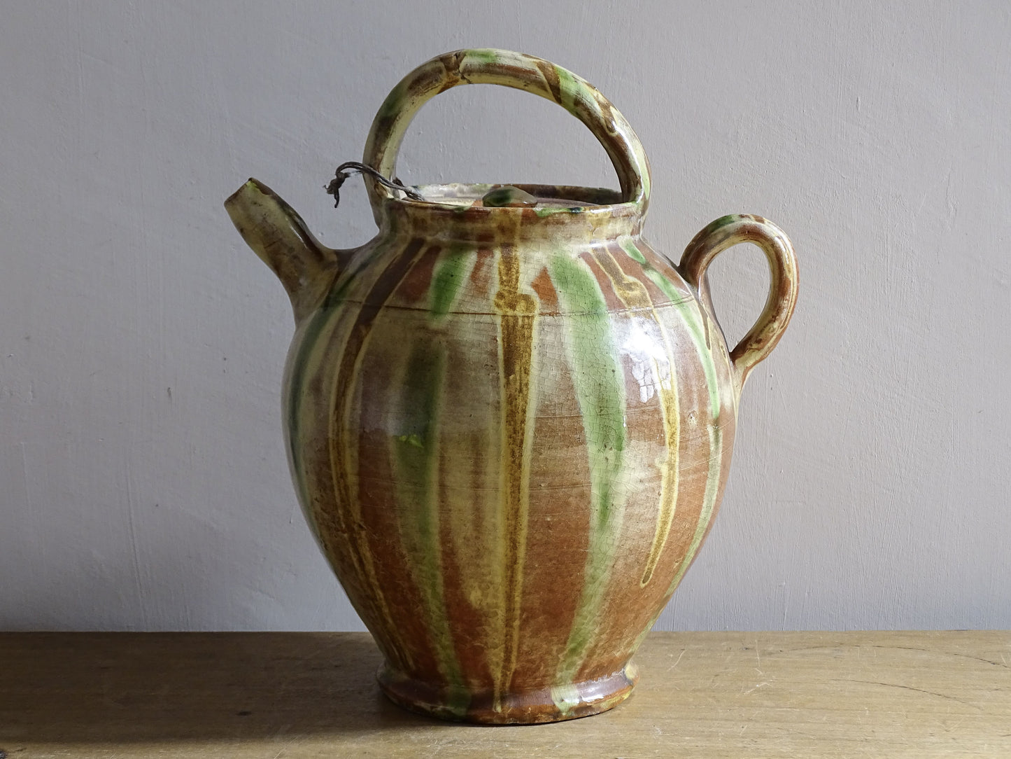 A French antique ceramic water jug or gargoulette from the South of France, dating to the late 19th century. This French antique gargoulette is formed in terracotta and finished with a flowing green and yellow glaze