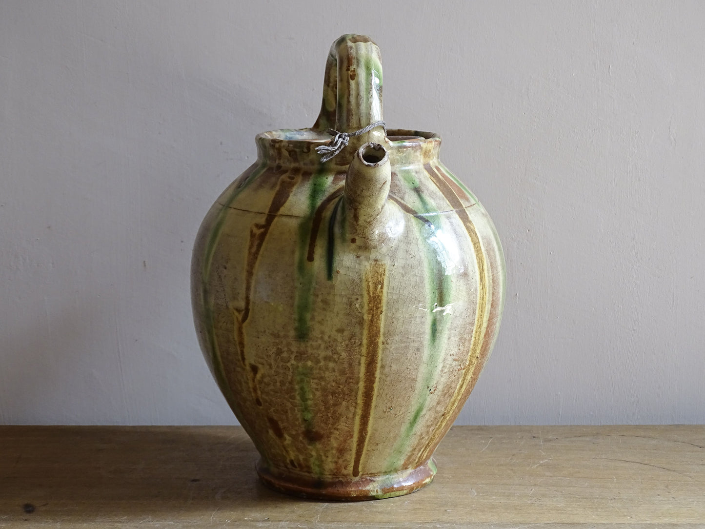 A French antique ceramic water jug or gargoulette from the South of France, dating to the late 19th century. This French antique gargoulette is formed in terracotta and finished with a flowing green and yellow glaze