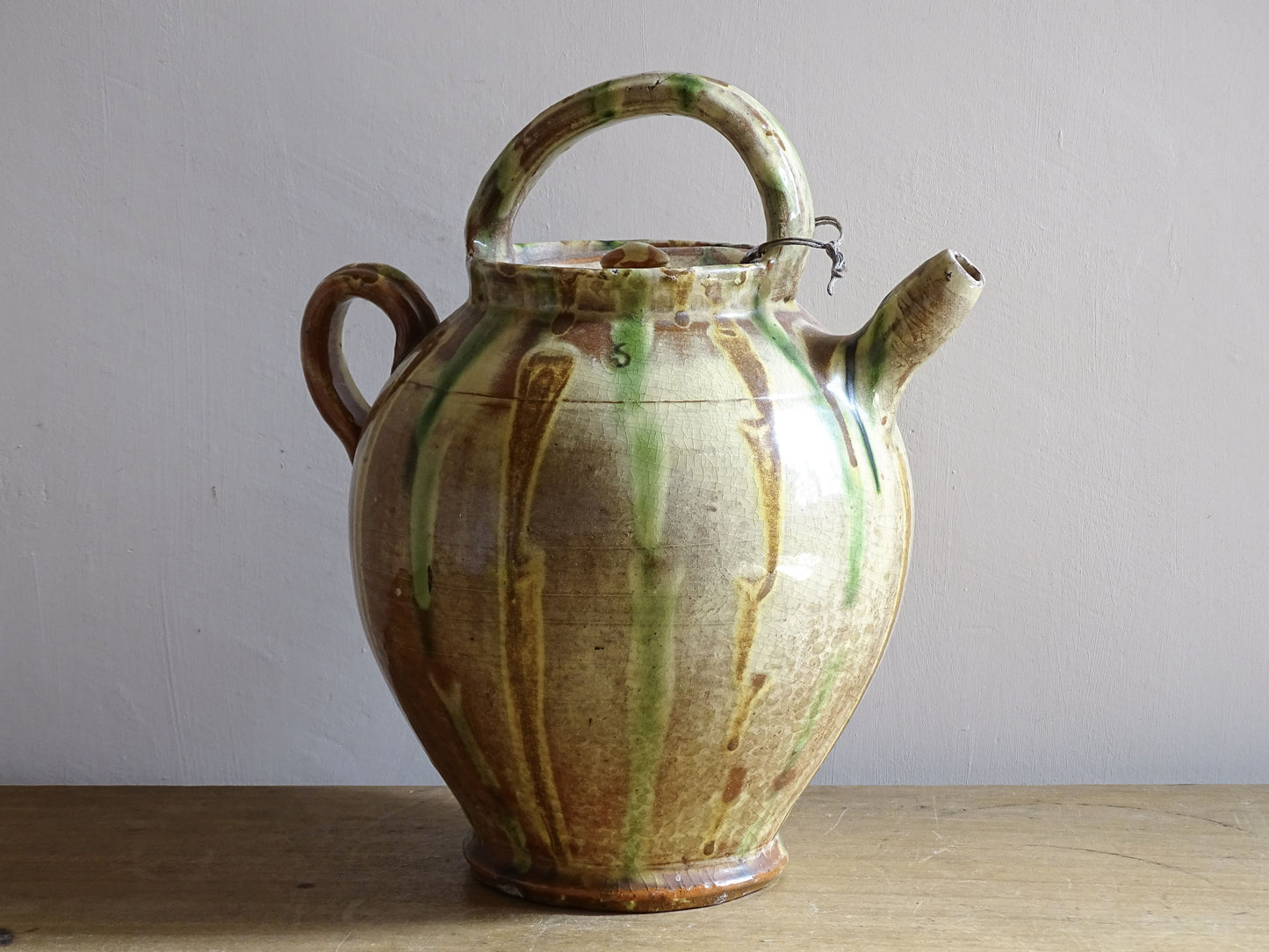 A French antique ceramic water jug or gargoulette from the South of France, dating to the late 19th century. This French antique gargoulette is formed in terracotta and finished with a flowing green and yellow glaze