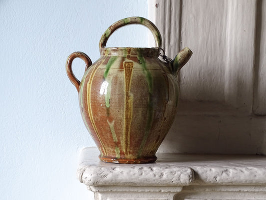 French antique pottery cruche or gargoulette with yellow, brown and green drip glaze. Displayed on a country house fireplace mantel