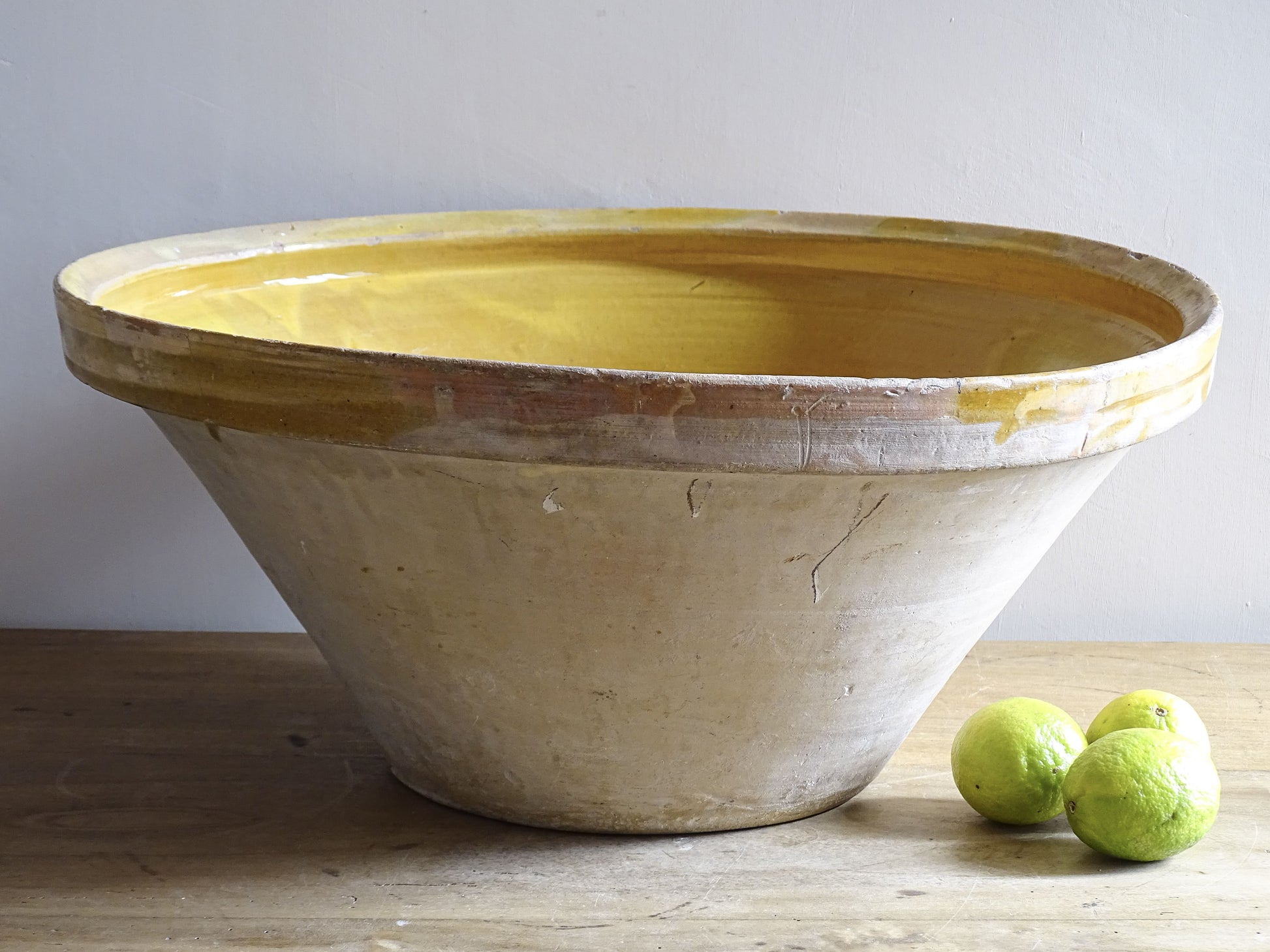 A large French antique tian bowl in pale terracotta, finished with a warm yellow glazed interior. Hand-thrown with a wide, gently flared form and a thick rolled rim. This tian bowl is typical of traditional farmhouse pottery from the South West of France.