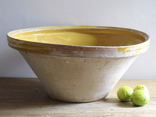 A large French antique tian bowl in pale terracotta, finished with a warm yellow glazed interior. Hand-thrown with a wide, gently flared form and a thick rolled rim. This tian bowl is typical of traditional farmhouse pottery from the South West of France.
