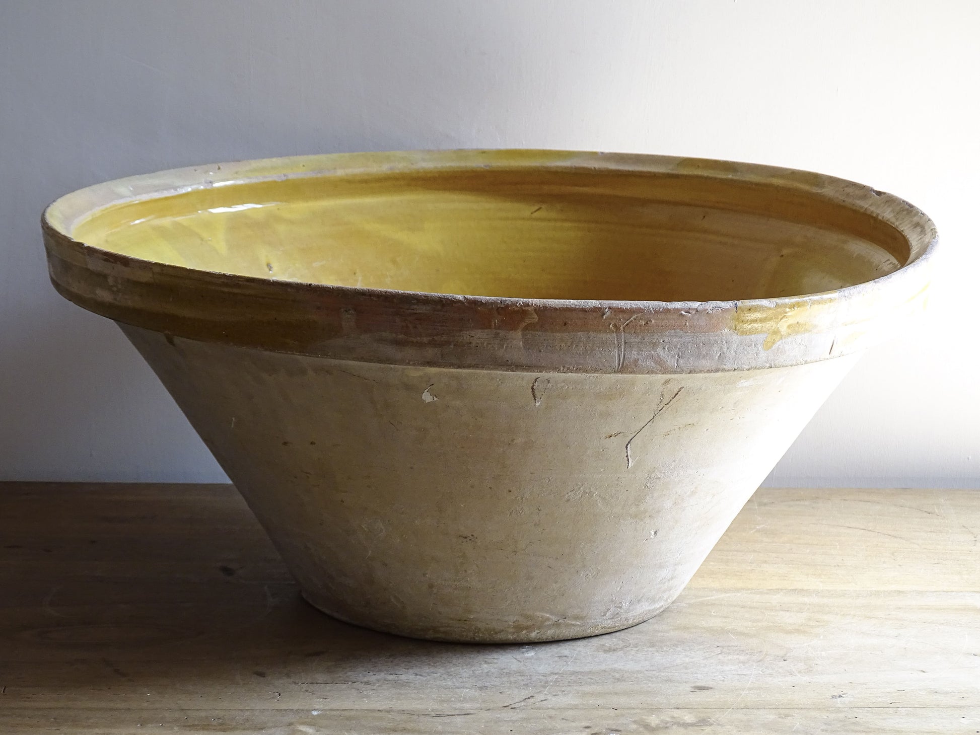 A large French antique tian bowl in pale terracotta, finished with a warm yellow glazed interior. Hand-thrown with a wide, gently flared form and a thick rolled rim. This tian bowl is typical of traditional farmhouse pottery from the South West of France.