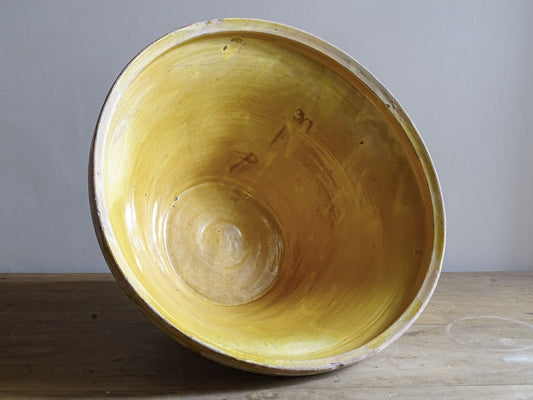 A large French antique tian bowl in pale terracotta, finished with a warm yellow glazed interior. Hand-thrown with a wide, gently flared form and a thick rolled rim. This tian bowl is typical of traditional farmhouse pottery from the South West of France.