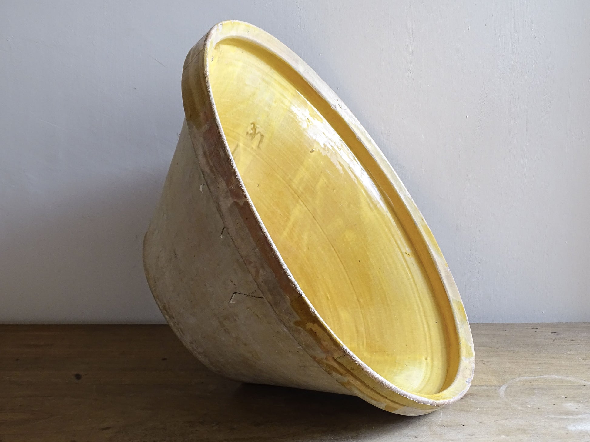 A large French antique tian bowl in pale terracotta, finished with a warm yellow glazed interior. Hand-thrown with a wide, gently flared form and a thick rolled rim. This tian bowl is typical of traditional farmhouse pottery from the South West of France.