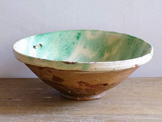 Rustic French pottery colander with pierced holes and terracotta base