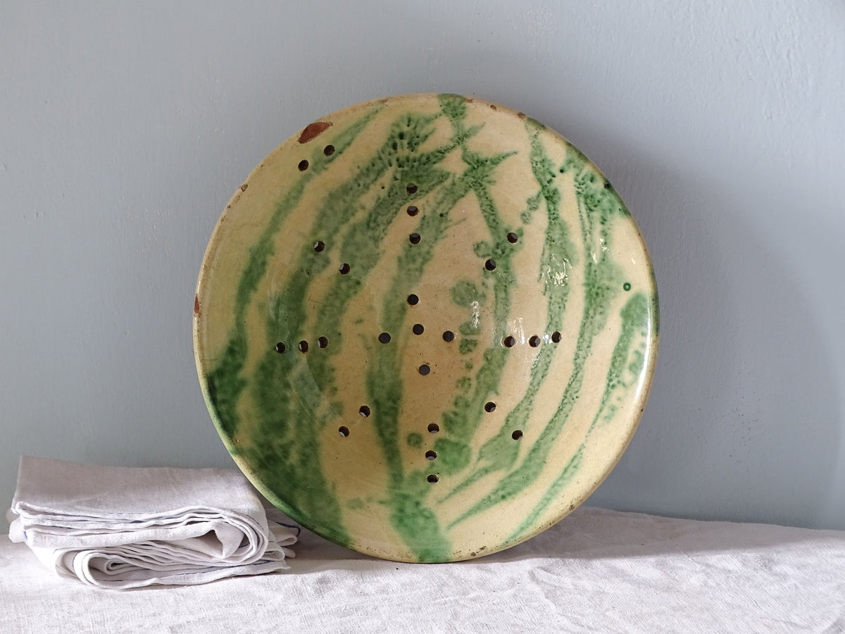 French antique glazed earthenware colander with yellow and green glaze. Pictured with antique linen.