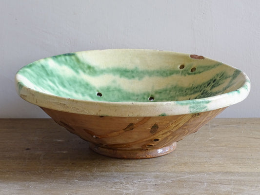 Rustic French pottery strainer bowl with pierced holes and footed base