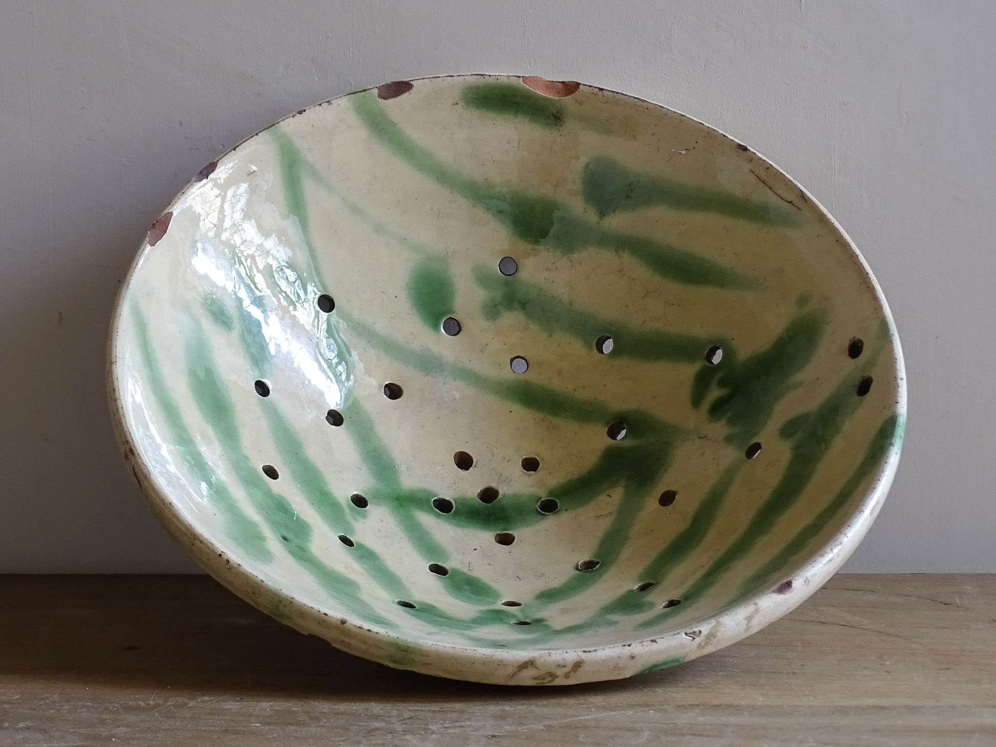 Large vintage French ceramic draining bowl in green glazed earthenware