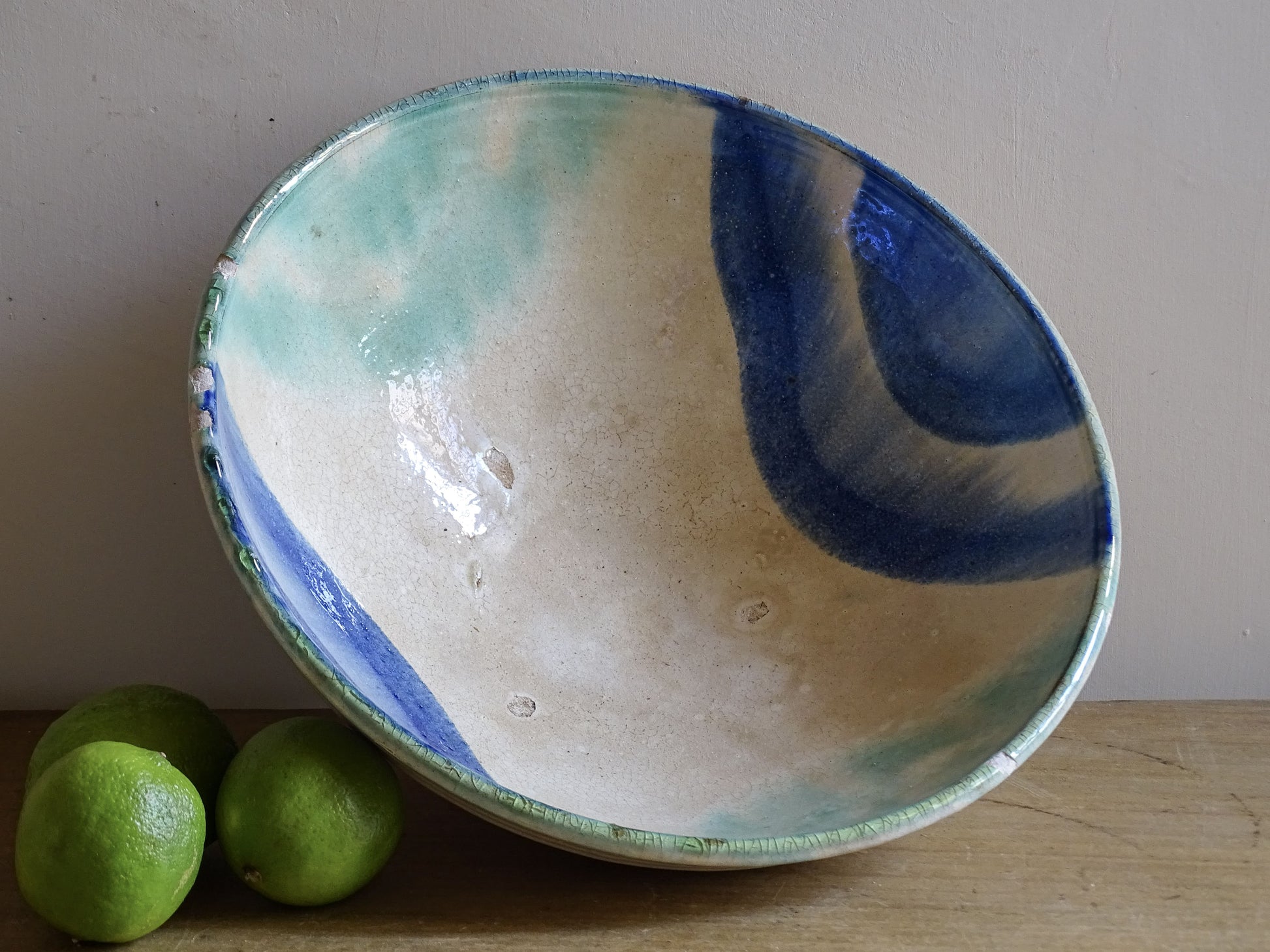 Vintage ceramic bowl with blue and turquoise glaze on cream background