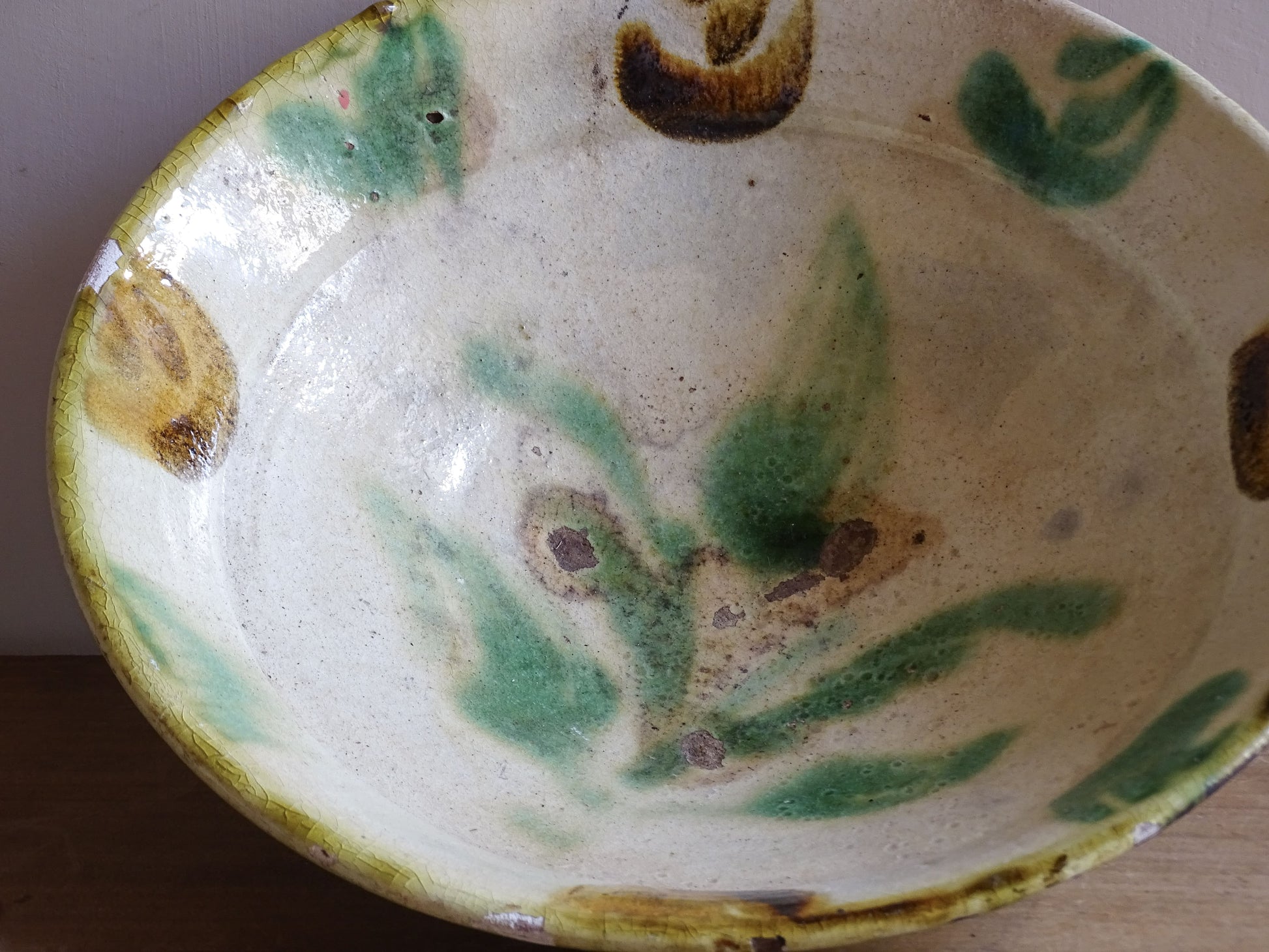 Large rustic French pottery bowl with hand painted green decoration and worn rim
