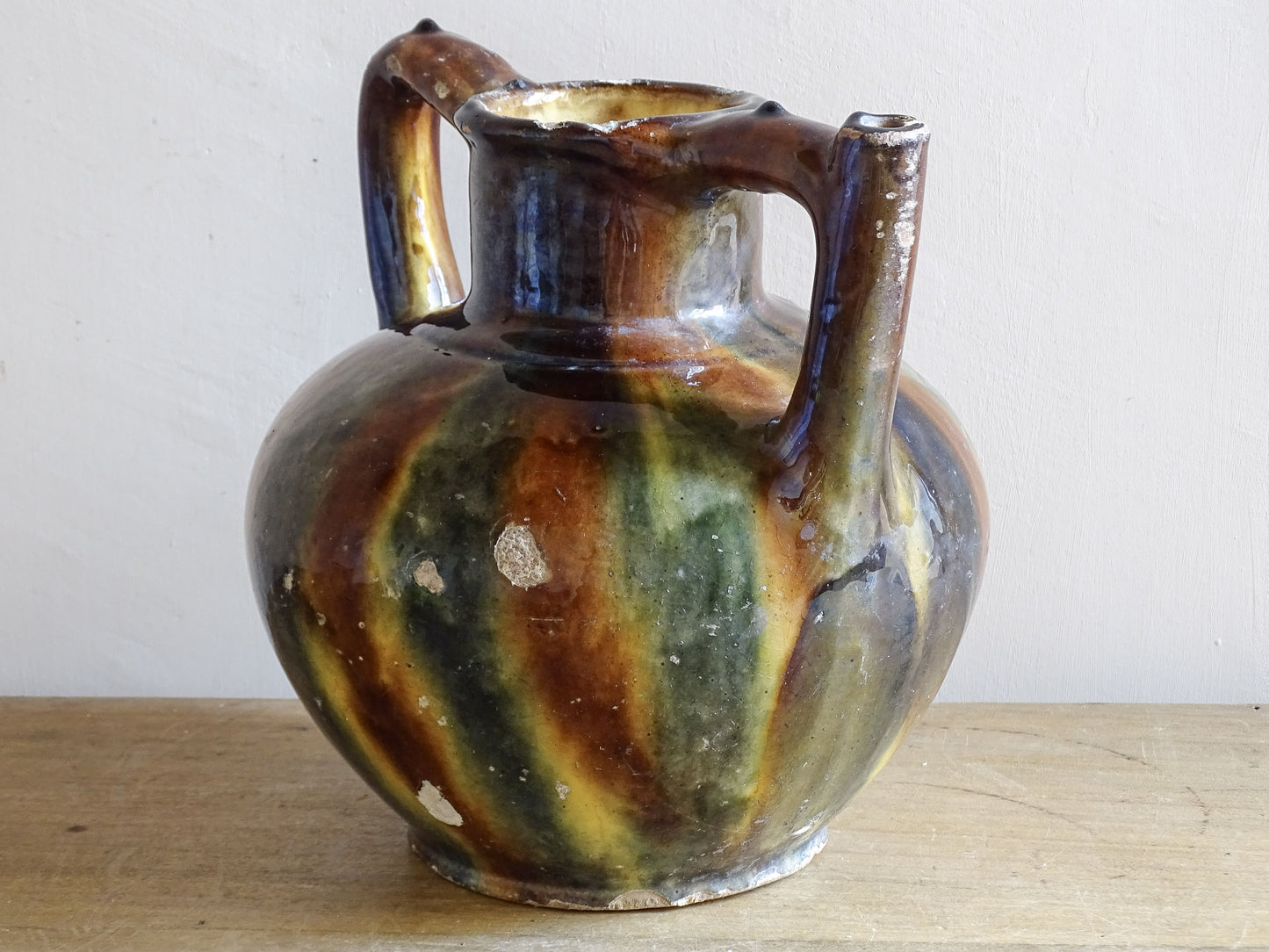 Rustic French pottery jug with twin handles and variegated green brown glaze