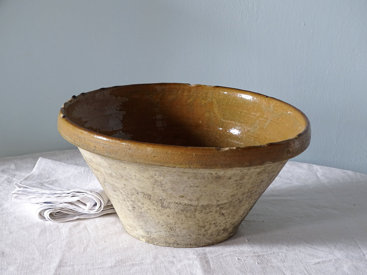 French antique earthenware ceramic tian bowl with yellow glazed interior, pictured on a country table with linen