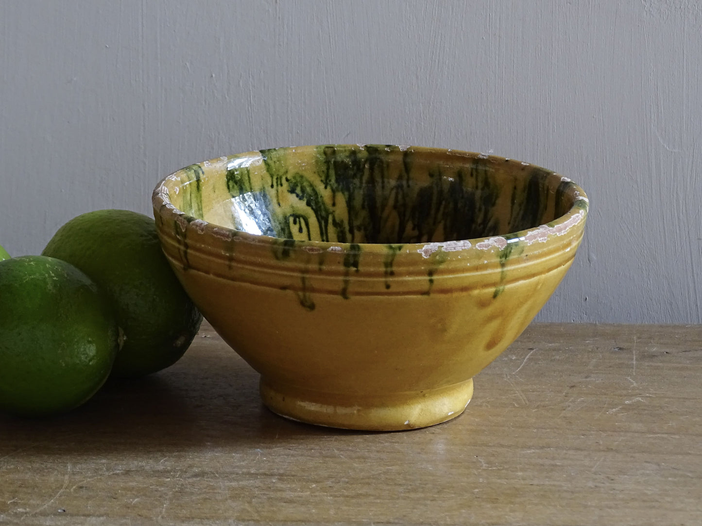 A small French antique terracotta bowl with a striking yellow ochre glaze and a traditional green jaspé decorated interior. Hand-thrown in earthenware.