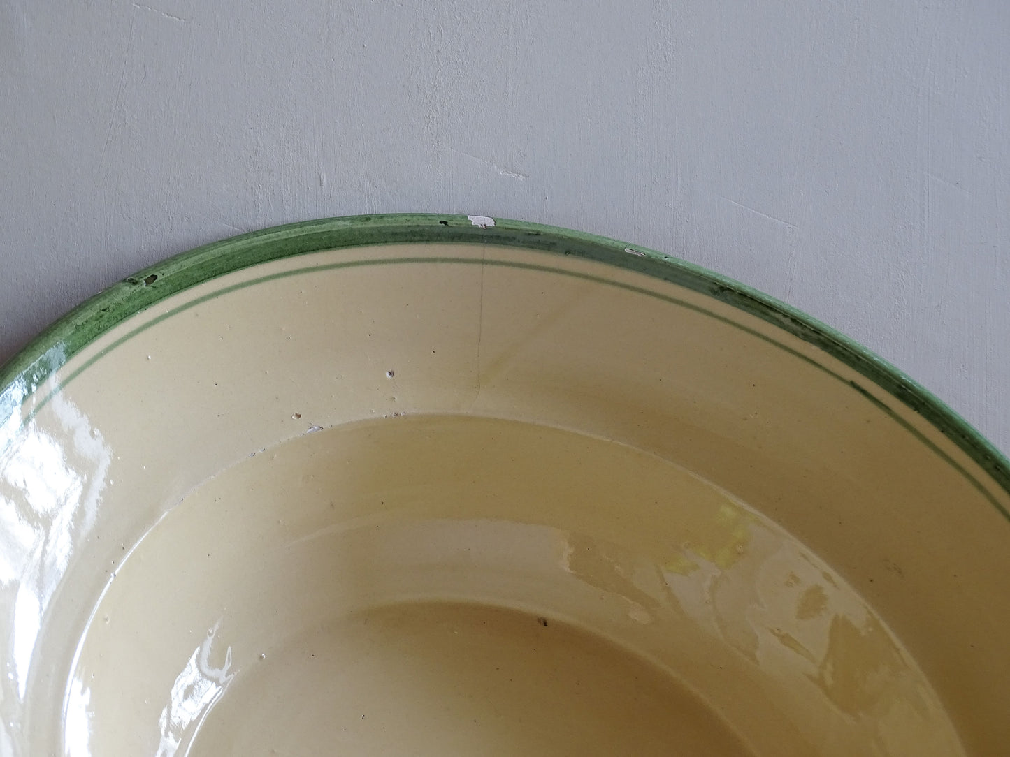   A large French  vintage  bowl  made from glazed terracotta with a warm honey-toned exterior, a soft cream glazed interior and a traditional green rim. 