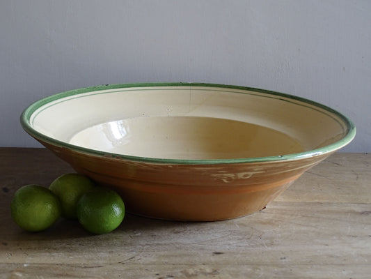  A large French  vintage  bowl  made from glazed terracotta with a warm honey-toned exterior, a soft cream glazed interior and a traditional green rim. 