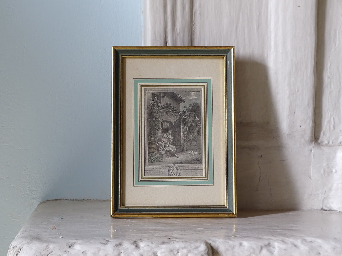 French Antique Engraving “Les Amours Champêtres” After Baudouin in gold frame, pictured on a country house fireplace